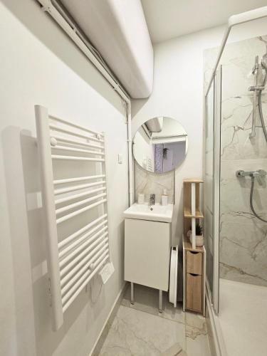 a white bathroom with a sink and a mirror at Le Charme Rosé in Villejuif