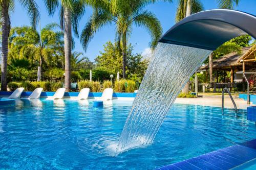 a water fountain in a swimming pool with palm trees at Hotel Termal Emperatriz Termas de Río Hondo in Termas de Río Hondo