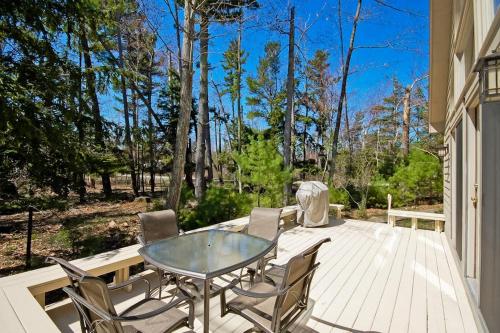 a patio with a glass table and chairs on a deck at Creeping Snails in Glen Arbor