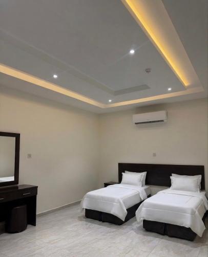 a bedroom with two beds and a flat screen tv at بستان الورد 2 in Taif