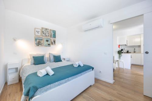 a white bedroom with a large bed with blue sheets at SagresSeaHouse in Sagres