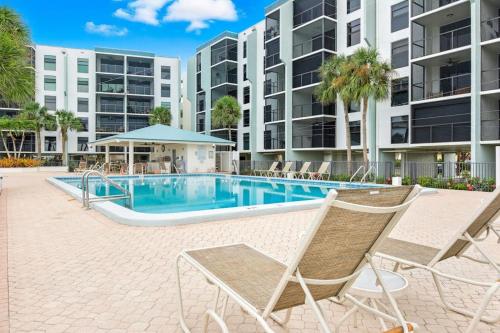 a swimming pool with two chairs in front of a building at Marco Magic in Marco Island