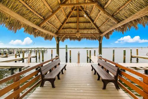 a wooden pier with benches and a thatched roof at Marco Magic in Marco Island