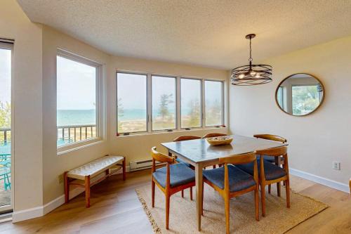 a dining room with a table and chairs and windows at South Beach 25 in Glen Arbor
