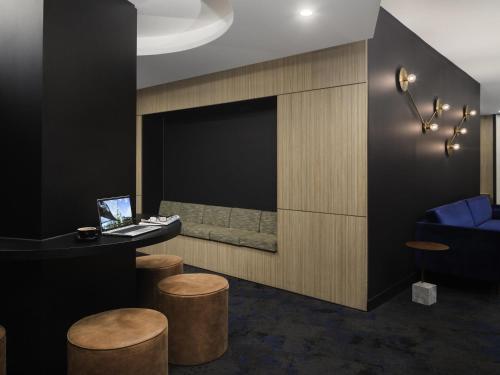 a lobby with a bar with stools and a laptop at Mercure Melbourne City Centre in Melbourne