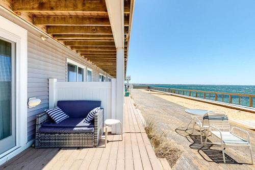 a porch with a chair and a table on the beach at Nautical Haven at Seaside in North Truro