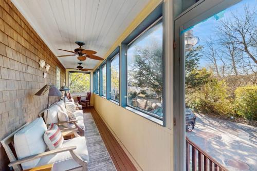 a screened porch with a ceiling fan and windows at Wraparound Hideaway in Provincetown