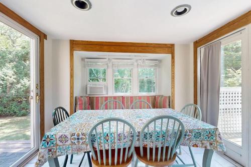 a dining room with a table and chairs and windows at esCAPE in Eastham