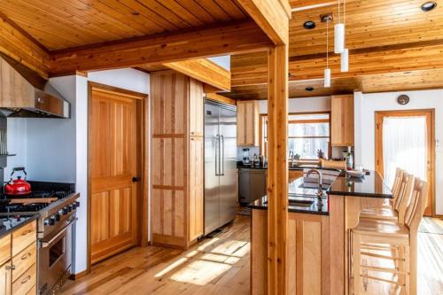 a large kitchen with wooden walls and wooden floors at Chalet Du Bois in Harbert
