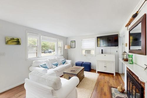 a living room with white furniture and a fireplace at The Kettle Cottage in Cotuit