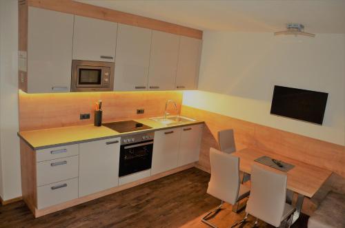 a kitchen with white cabinets and a table and a television at Green Apart in Uderns