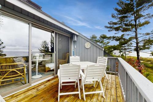 a porch with white chairs and a table on a balcony at Wilderness 9 in Glen Arbor