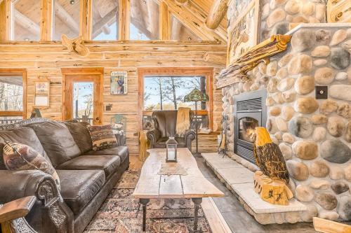 a living room with a stone fireplace in a log cabin at Salmon Run in Thompsonville