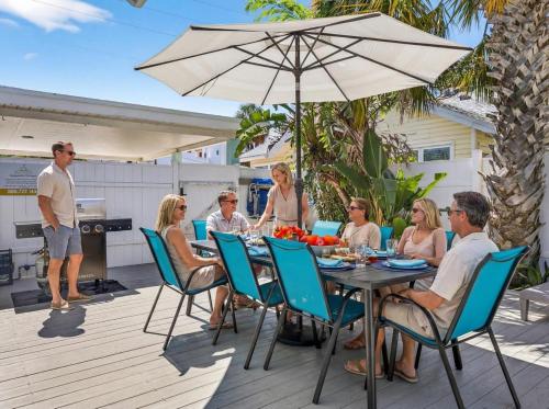 a group of people sitting around a table with an umbrella at Coastal Beach Retreat in Clearwater Beach