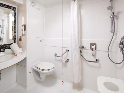 a white bathroom with a toilet and a shower at ibis London Wembley in London