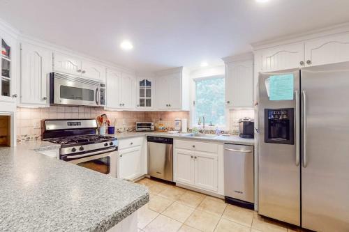a kitchen with white cabinets and stainless steel appliances at Life's Better at the Beach in Eastham