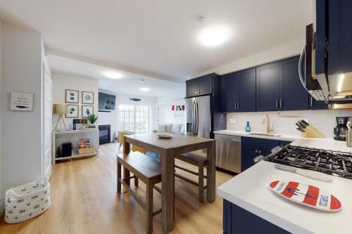 a kitchen with blue cabinets and a table and a counter at Villa Balena - A Cape Cod Oasis in Dennis Port