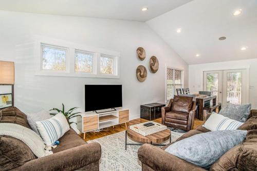 a living room with two couches and a flat screen tv at Borrowed Thyme in Saugatuck
