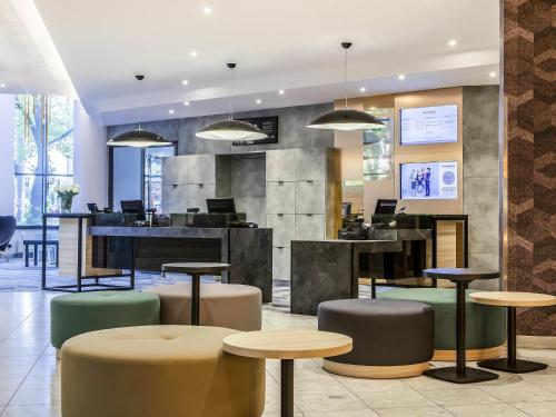 a lobby with tables and stools in a building at Novotel Szczecin Centrum in Szczecin