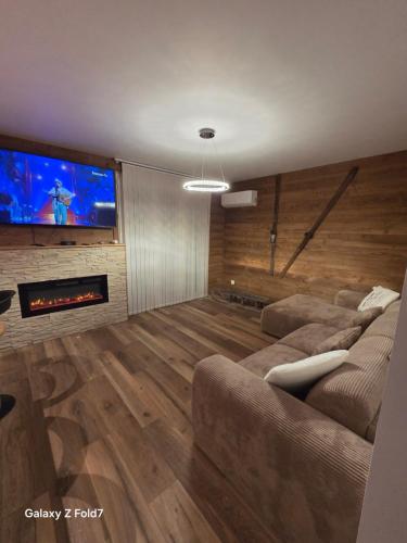 a living room with couches and a large tv at JOLYKa résidence avec caméra et digicode possibilité location voiture Mercedes, garage ,climatisation ,cheminée, Netflix, petit déjeuner ,repas du soir fondue, raclette, barbecue sur demande in Albertville