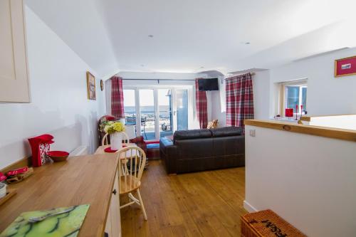 une cuisine et un salon avec un canapé et une table dans l'établissement Farneholm Annex Cottage, à Beadnell