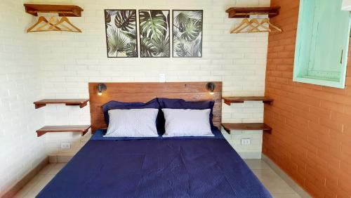 a bedroom with a blue bed with two white pillows at Suite na Natureza com Café da Manhã in São Pedro