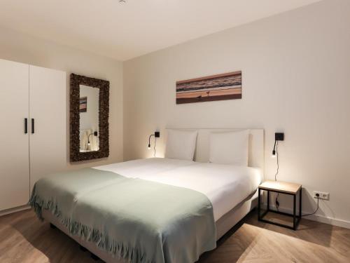 a bedroom with a large white bed and a mirror at Zilte Haven in Kamperland