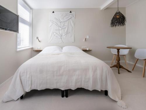 a white bedroom with a bed with a white comforter at Duinsuite in Oostkapelle