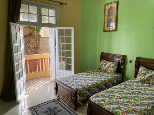 a bedroom with two beds and an open door at Villa Sais avec piscine in Meknès