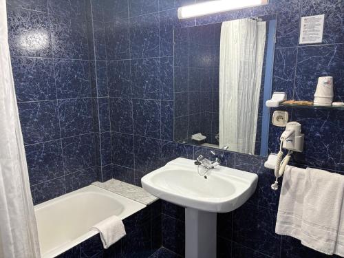 a blue tiled bathroom with a sink and a tub at Hotel Folch in Sant Julià de Lòria