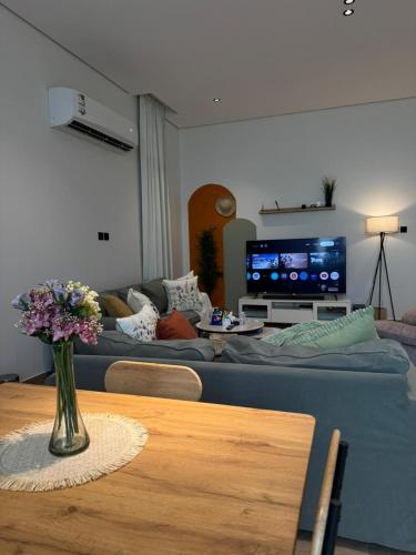 a living room with a couch and a table with flowers at شقة الدانة وصول ذاتي القيصومه in Hafr Al-Batin