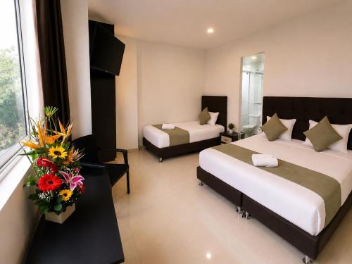 a hotel room with two beds and flowers in it at Raí home in Medellín