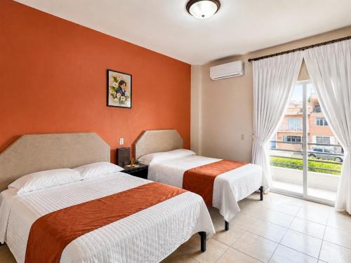 a hotel room with two beds and a window at Hotel Valle del Huajucar in Calvillo