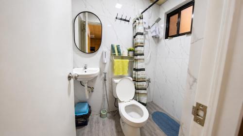 a bathroom with a toilet and a sink and a mirror at CLBC Residences 1A in Ibaba
