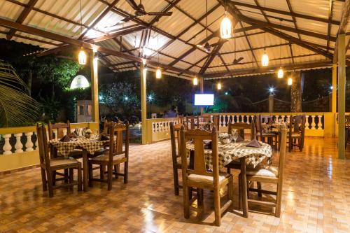 a dining room with tables and chairs and a television at Cochichos Resort in Vagator