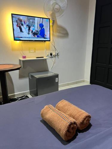 a bedroom with a bed with a tv and a towel at Little Chenang Cottage Motel Langkawi in Pantai Cenang