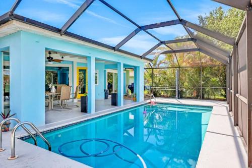 an indoor swimming pool with a blue ceiling and glass walls at Three Palms Retreat in Cape Coral