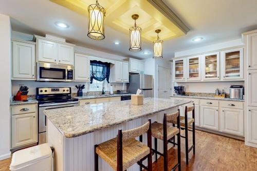 a kitchen with white cabinets and a island with bar stools at Rehoboth Beach --- 18 Sabrina Dr in Lewes