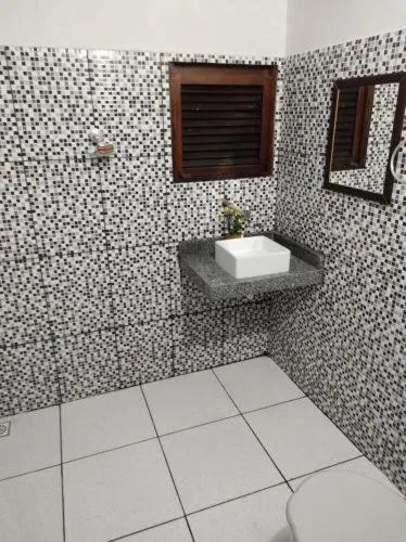 a bathroom with a sink and a tiled wall at cantinhoannajullyaatins in Atins