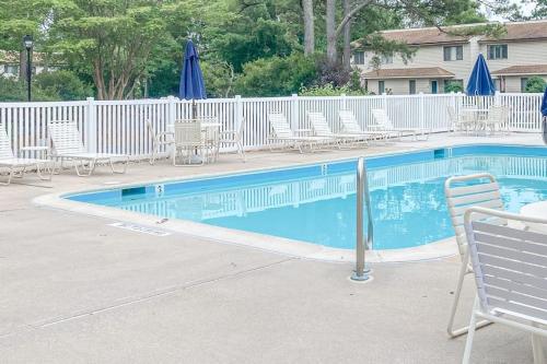 a swimming pool with chairs and umbrellas at Bethany Pines - 431 Bethany Pines in Bethany Beach