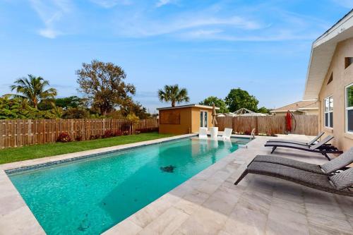 a swimming pool with chairs and a fence at Mango House in Naples