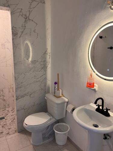a white bathroom with a toilet and a sink at Casa completa, 4 dormitorios, 7 camas dobles, 4 sofá cama, 3 baños 1 en planta baja, cocina equipada, consola Arcade, asador, juguetes para niños, plancha, secadora, cafetera, etc, fraccionamiento privado, zona de vías rápidas y toallas in Torreón