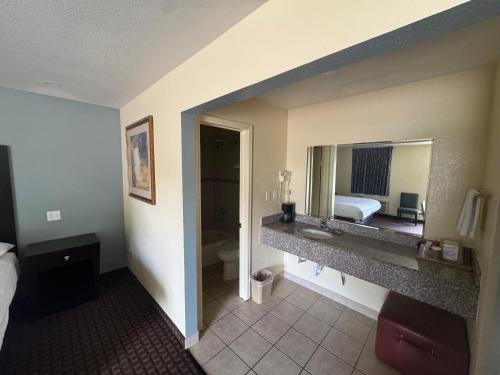 a hotel room with a bathroom with a bed and a mirror at Village Inn in Ada