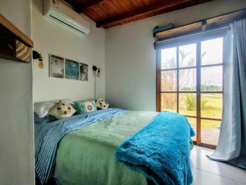 a bedroom with a bed with a blue blanket and a window at Luz Marina Cabaña Pettit Hidromasaje in Punta Colorada