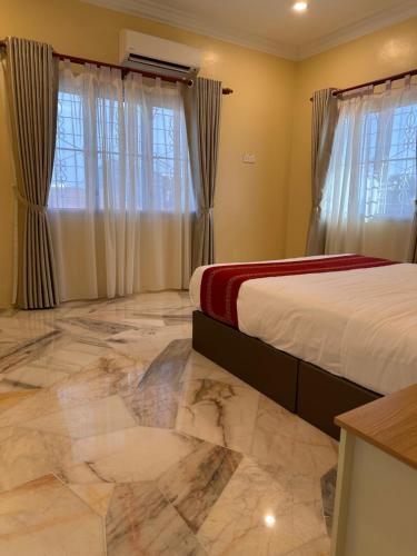 a bedroom with a bed with marble floors and windows at UncleLiew Cozy Home 老刘民宿 in Sekinchan