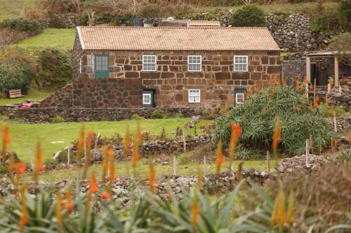 a stone house with a garden in front of it at Caldeira Guesthouse in Fajã da Caldeira de Santo Cristo
