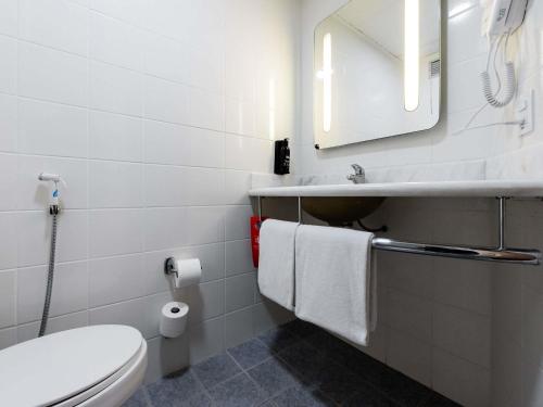 a bathroom with a toilet and a sink and a mirror at ibis Joinville in Joinville
