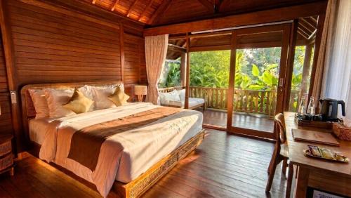 a bedroom with a large bed and a balcony at The Woods Uluwatu in Uluwatu