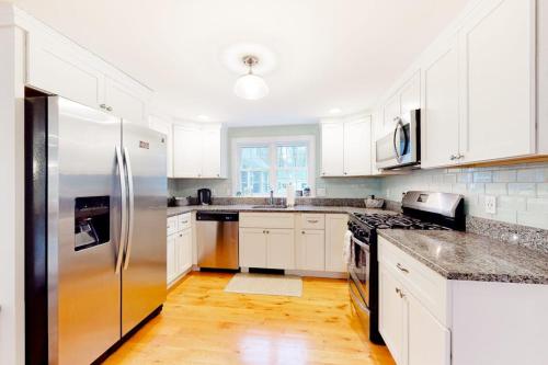 a kitchen with white cabinets and a stainless steel refrigerator at Lisa Lane in Mashpee