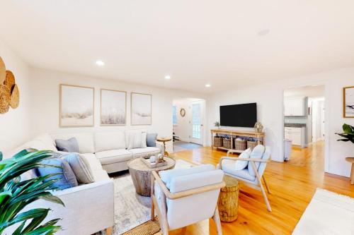 a living room with white furniture and a flat screen tv at Lisa Lane in Mashpee